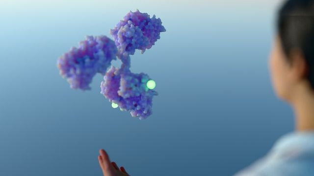 Scientist observing a floating 3D-rendered antibody-drug conjugate (ADC) structure with glowing markers, symbolizing targeted therapy. 