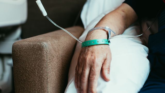 A persons arm resting on a pillow with an IV drip delivering chemotherapy. 