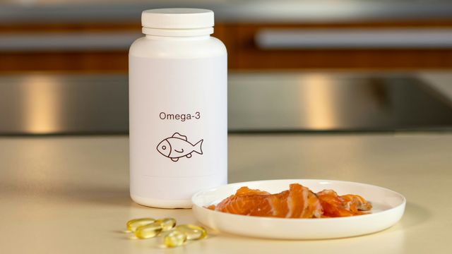 A pill bottle and some omega-3 pills, next to a small plate of salmon slices. 