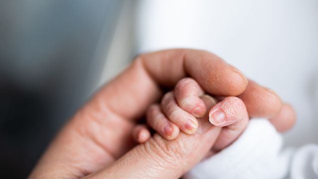 An adult holding a baby's hand, signifying the first patient to receive a customized gene therapy was a child. 