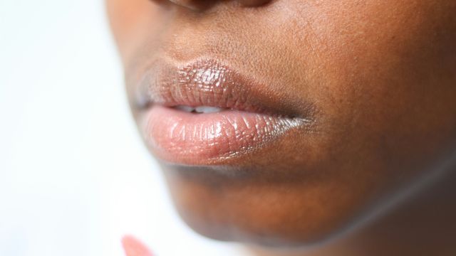 A close-up photograph of a Black woman's mouth and chin. 