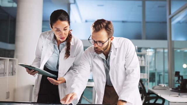 Male and female researchers reviewing data in a lab, discussing scientific retraction rates. 