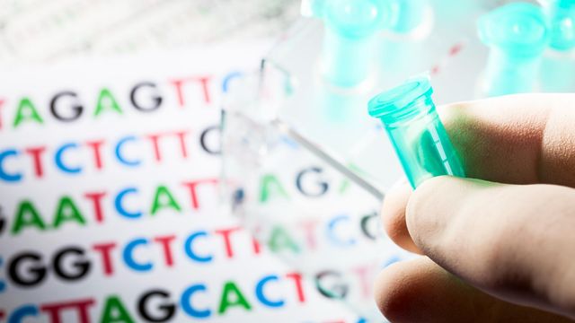 Gloved hand holding a small laboratory vial against a background of colorful DNA sequencing data, representing next-generation sequencing technology 