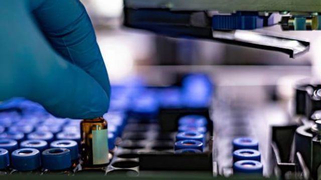 Close up of a womens hand in a glove with a test tube.  