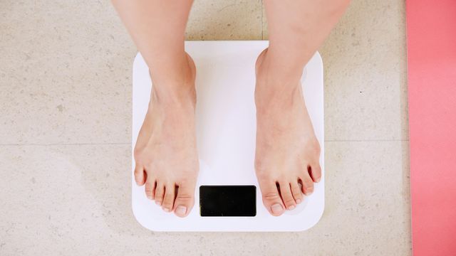 Person standing on a white digital scale, symbolizing weight monitoring for bariatric surgery. 