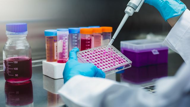 Close up of lab worker working with in vitro diagnostic equipment and pipette 