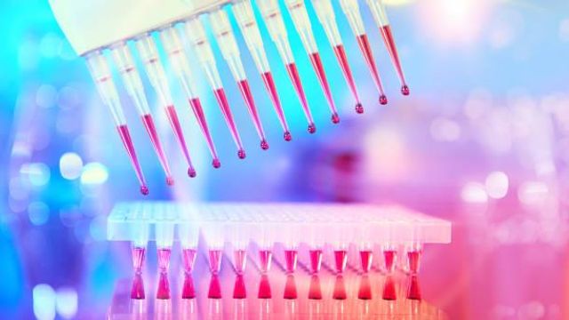 Multichannel pipette dispensing red liquid into tubes under bright neon lighting, creating a futuristic lab atmosphere. 