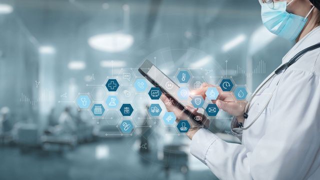 Healthcare worker using a tablet with digital icons across the image. 