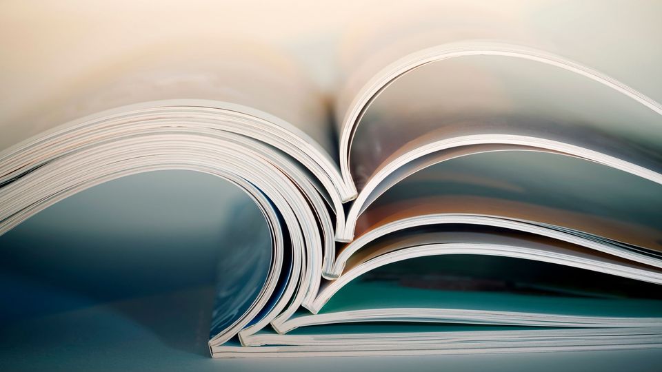 Stack of open academic journals showing glossy pages, representing scholarly publishing.