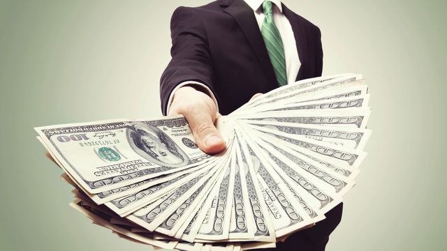 Business man in suit holding money in a fan shape. 